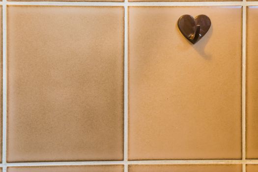 old vintage plastic hanger on retro tiling in the bathroom, retro hook for hanging the towel, bathroom architecture background