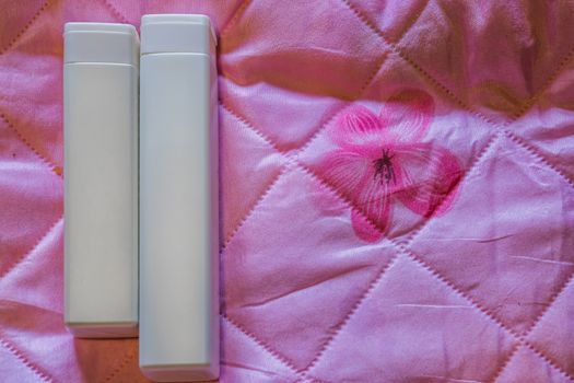 cosmetic products, two blank white bottles isolated on a pink background