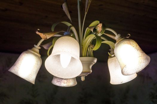 closeup of a vintage chandelier decorated with flowers, retro home interior decoration, lamp shining light, indoor architecture background