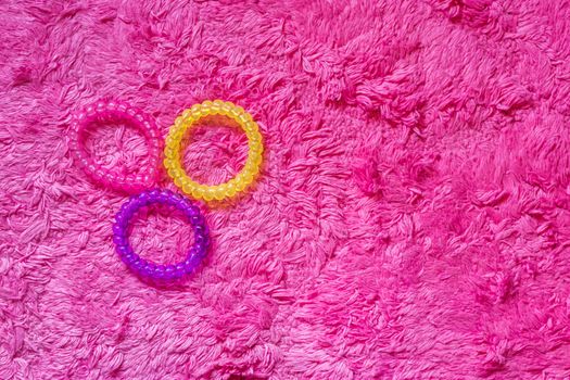 Three plastic cable hair elastics in different colors isolated on a pink background, girl hair style accessories