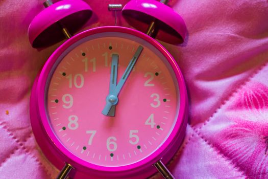 macro closeup of a pink vintage alarm clock on a pink background