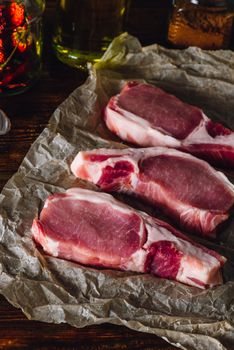 Three Pork Loin Chops on Parchment. Vertical Orientation.