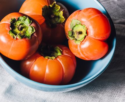 Blue Bowl with Ripe Persimmons on White Textile