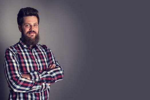 Smiling bearded man in checked shirt, portrait, studio shot on gray background