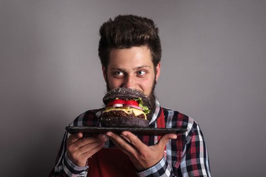 Man smelling fresh self made black burger close up