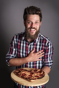 Happy smiling man gives burned heart shaped pizza