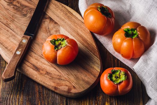 Persimmons with Knife on Wooden Cutting Board