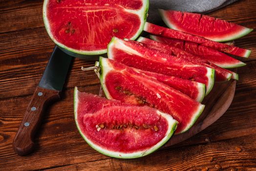 Watermelon slices with knife lying on the cutting board