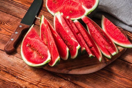 Watermelon half and slices lying on wooden table. Juicy dessert.