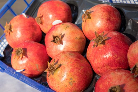 Box of pomegranates sold at the market during a sunny day.