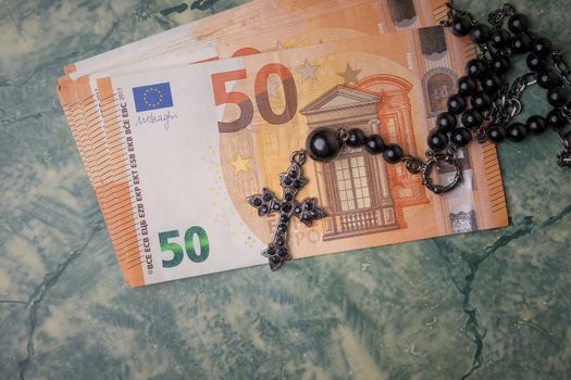 Black rosary and euro money on green table,concept photo.