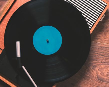 Older Gramophone with a vinyl record on wooden table, top view  close up,vintage style.