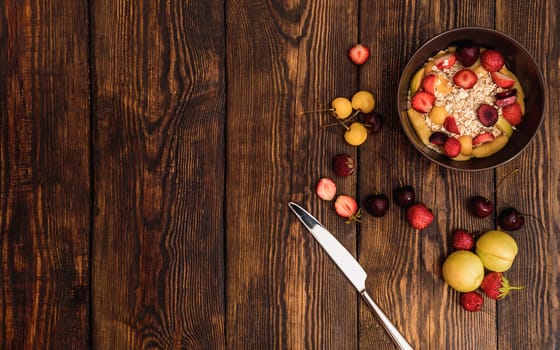 Breakfast with porridge, fruits and berries on weathered wooden textured table on background or old panels with cracks, scratches, swirls