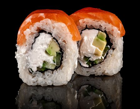 Two pieces of sushi rolls Philadelphia. Black background. Reflection.