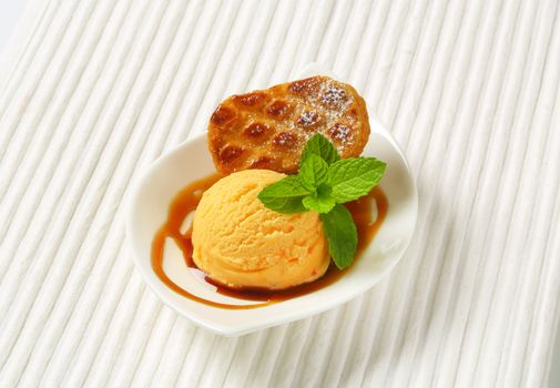 Small almond filled cookie served with caramel sauce and scoop of ice cream