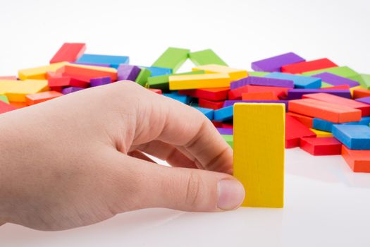 Hand playing with colored domino on white background