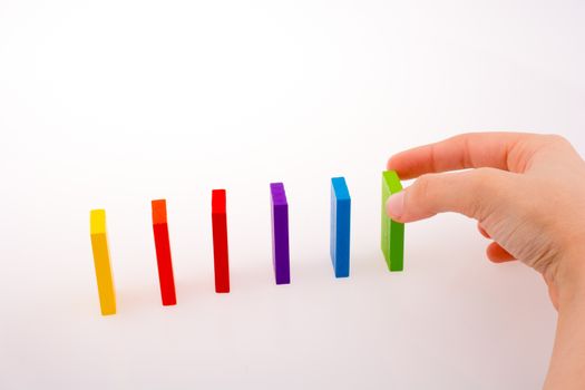 Hand playing with colored domino on white background