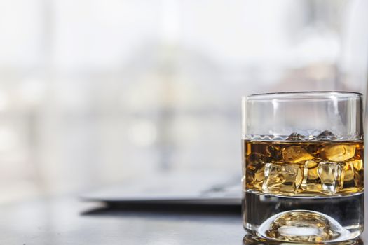 A glass of alcohol near laptop on table