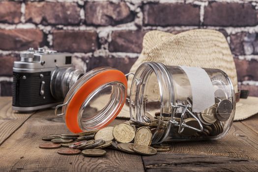 Jar and coins on wood table and brick background