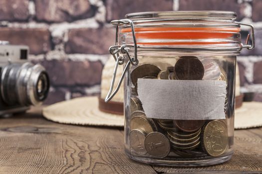 Coins in jar on wood table and brick background