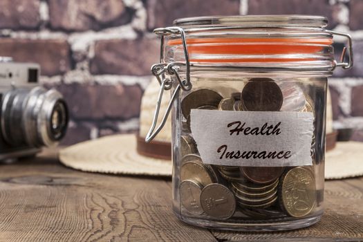 Coins in jar on wood table and brick background