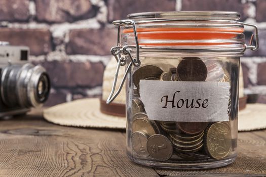 Coins in jar on wood table and brick background