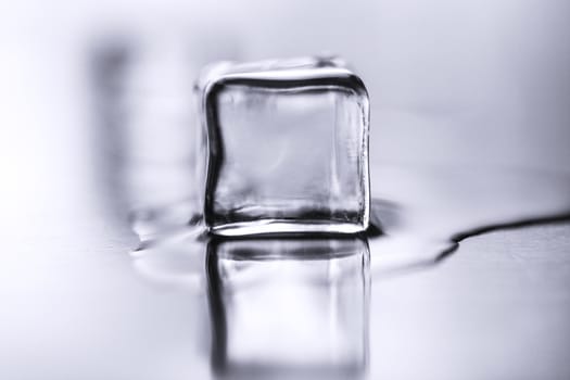 Ice cube melts on table with reflection