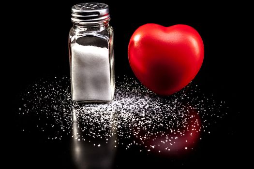 Salt and heart isolated on black background with reflection