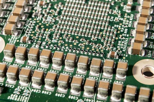 Small electronic components on green circuit board macro closeup