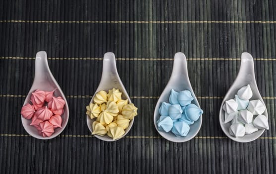 Colorful sweets in cups on dark wood