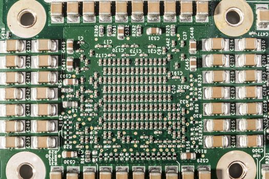 Small electronic components on green circuit board macro closeup