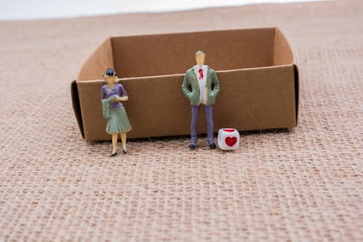 Tiny figurine of man and woman model beside a box