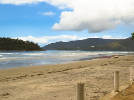 View of the beach in clear day with the coast and island in the background, blue sky with clouds in Brazil.