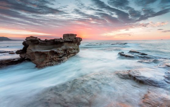 The rock seemingly floats like a boat leaving a wake behind it with the fast rushing tidal ocean currents whooshing by