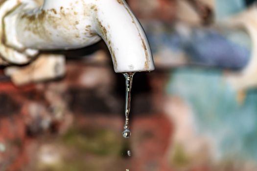 Fresh water leaking from old plastic pipe. Close up. Isolated from background. Household water conservation Concept.