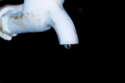 Fresh water leaking from old plastic pipe. Close up. Isolated from background. Household water conservation Concept.