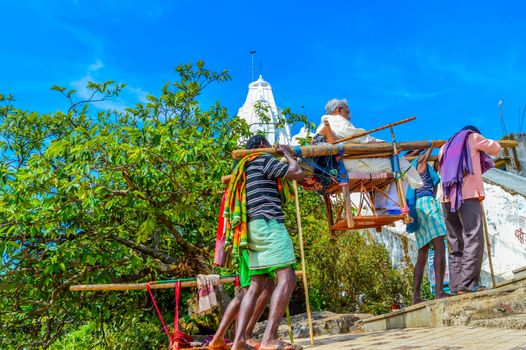 RANCHI, JHARKHAND, INDIA- MAY, 2017: Porters carry a tourist seated in sedan chair in a hilly area to the ancient temple PARESHNATH temple.