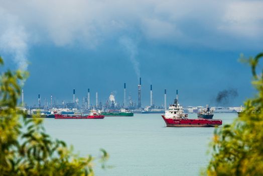 View of the Singapore Strait from Sentosa Island. Ships, industrial landscape and stormy weather.