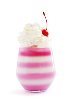 Pink striped jello dessert in glass with whipped cream and red candied cherry on top isolated on white background