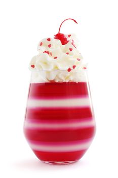 Red striped jello dessert in glass with whipped cream, red candied cherry and heart shape confectionery on top isolated on white background, Valentines day