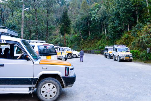 Tourist Cars parked on street side near pavement in sunny day. Kaushani, Himachal Pradesh, India, Asia.