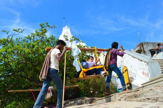 KEDARNATH, AMARNATH, INDIA- OCTOBER, 2017: Kashmiri porters carry Tourists seated in sedan chair during 3-day Himalayan pilgrimage to worship Shiva in a hilly area of ancient Amarnath Cave temple.