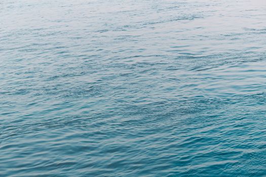 View of Clean flowing blue water surface with ripples and sunrays or sunlight reflections. Beautiful Adriatic Sea water shines at dusk light.Natural beauty Wave water texture design for background.