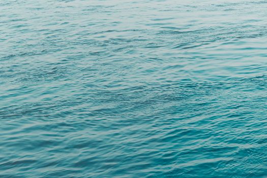 View of Clean flowing blue water surface with ripples and sunrays or sunlight reflections. Beautiful Adriatic Sea water shines at dusk light.Natural beauty Wave water texture design for background.