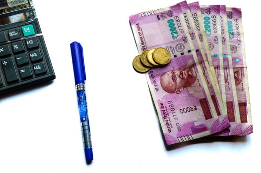 Focus on Gandhi. Indian paper currency rupees and coins stack, calculator and pen business growth symbol. Studio shot Isolated on white background close up. Planning budgeting funding concept, India.