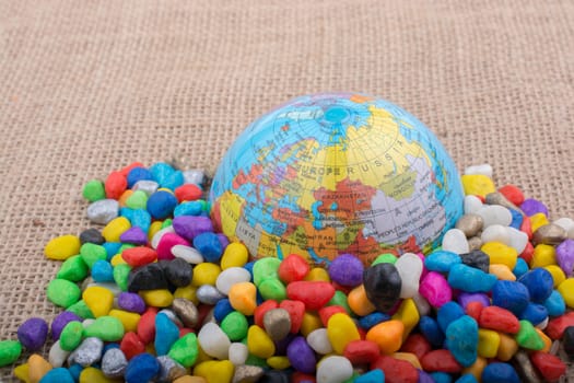 Model globe placed amid colorful pebbles