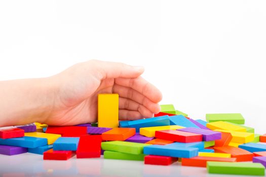 Hand playing with colored domino on white background