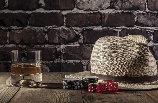 Hat, dice, chips and alcohol on wood table