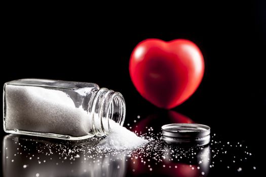 Heart and salt isolated on black background with reflection