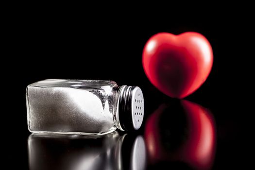 Heart and salt isolated on black background with reflection